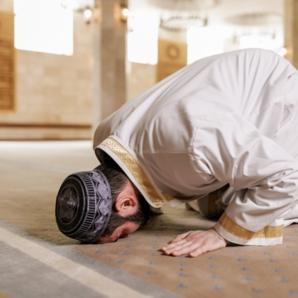 man in white thobe bowing down on the floor